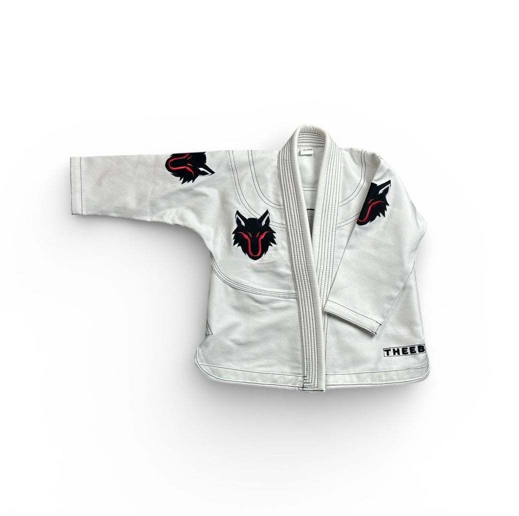 My Store THEEB Kids BJJ Gi, white 450 GSM cotton with embroidered wolf logos on sleeves and chest. Durable and flexible.