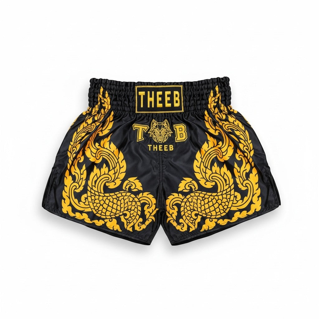 My Store THEEB Golden Age black Muay Thai shorts with gold traditional Thai art and elastic waistband.