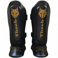 My Store black genuine cowhide leather shin guards with gold Theeb logo and text, designed for Muay Thai and MMA.