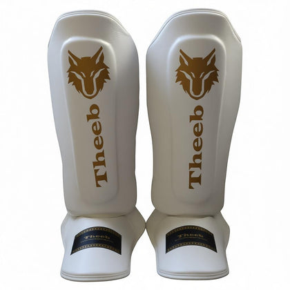 My Store THEEB Golden Age white genuine cowhide leather shin guards with gold wolf logo and padding for Muay Thai, MMA, sparring.