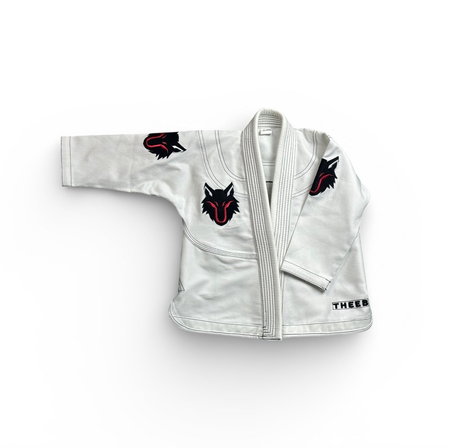 My Store THEEB Kids BJJ Gi, white 450 GSM cotton with embroidered wolf logos on sleeves and chest. Durable and flexible.
